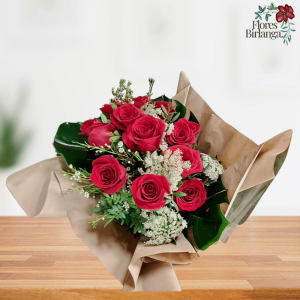 Ramo de 12 rosas rojas con flor de cera, amimajus, eucalipto y monstera, envuelto en papel kraft sobre mesa de madera